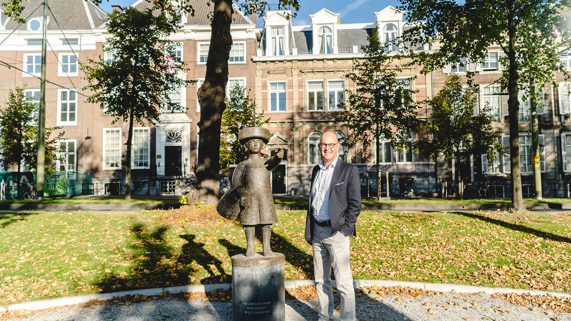 Joost Verbaas van SCOOP Makelaardij naast een standbeeld in Den Haag